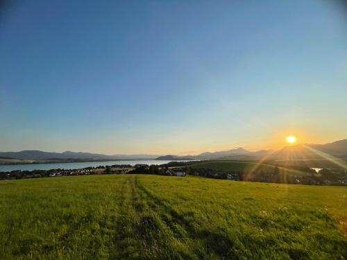 a field of green grass with the sun in the sky at Chaty pri Mare - Tatralake Houses near Auqapark Tatralandia and Lake Liptovska Mara in Liptovský Trnovec