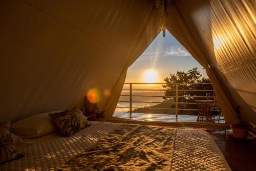 a bed in a tent with a view of the ocean at Quimera Glamping in Pacuar