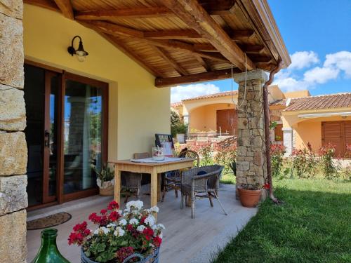 a patio with a table and chairs under a wooden pergola at Residenze di Via Magnolie in Porto Ottiolu