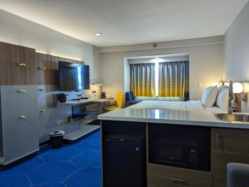 a hotel room with a bed and a kitchen with a sink at Microtel Inn & Suites by Wyndham Rapid City in Rapid City