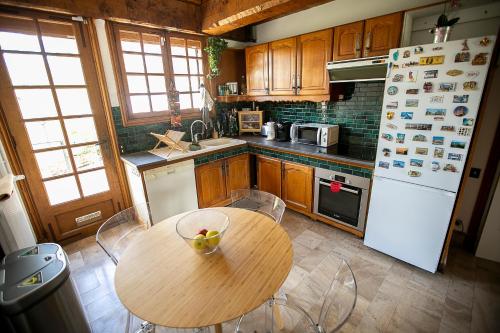 大瀑布城的住宿－Chambres d Hôte Bords de Seine Vernon-Giverny，厨房配有木桌和白色冰箱。