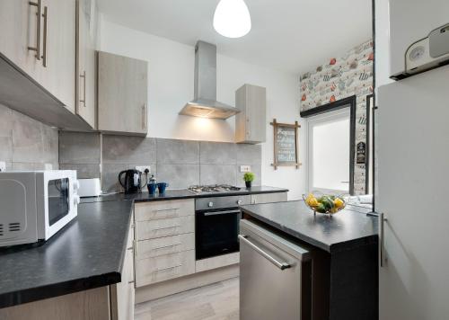 a kitchen with a microwave and a stove top oven at Newcastle CITY APT5,FREE STREET PARKING,4 BEDROOM HOUSE WITH 2 FULL BATHROOM AND KITCHEN,ALL ROOMS WITH TVs,7 BEDS,NETFLIX in Newcastle upon Tyne