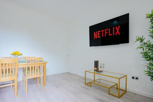 a dining room with a table and a tv on a wall at Modern Freshly Refurbed Home Luton in Luton