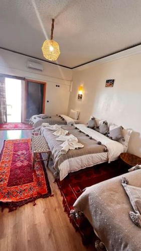 a group of beds in a room with a rug at RIAD TUMAST in Aït Slimane