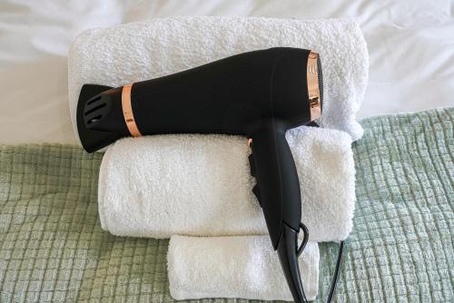a hair dryer sitting on top of towels at Modern Freshly Refurbed Home Luton in Luton