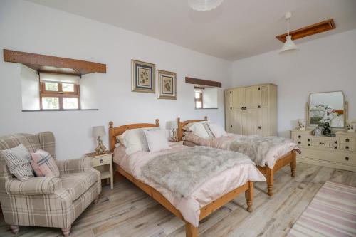 ブランプトンにあるTorties Cottageのベッドルーム1室(ベッド2台、ソファ、椅子付)