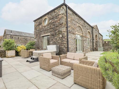 a patio with wicker furniture and a brick building at Hazel Cottage in Ulverston