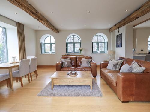 a living room with brown leather furniture and a table at Hazel Cottage in Ulverston