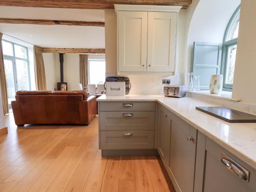 ウルバーストンにあるHazel Cottageの白いキャビネットとソファ付きのキッチンが備わります。