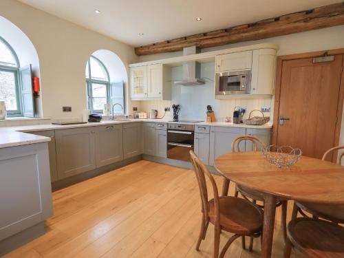a kitchen with a wooden table and a wooden floor at Hazel Cottage in Ulverston