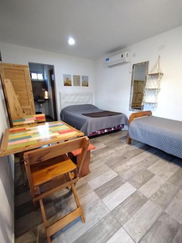 a room with two beds and a table and a desk at Las Marilubis Calamuchita in Santa Rosa de Calamuchita
