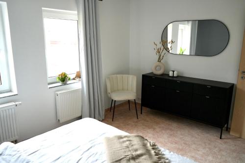 una camera da letto con specchio, cassettiera e sedia di Berga Farmhouse a Berga