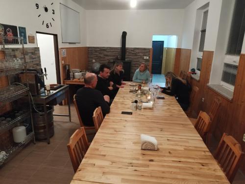 a group of people sitting around a long wooden table at Penzion U Lipna in Přední Výtoň