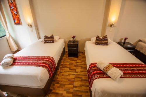 two beds in a hotel room at RUMIQOLQA Machupicchu Hotel in Machu Picchu