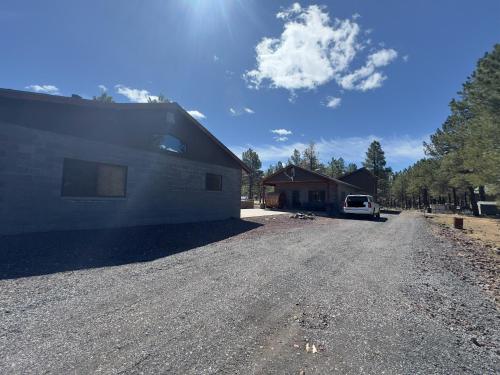 a house with a car parked next to a gravel road at Rustic Retreat New Cabin on 2 Acres Fully Fenced! Summer special 2 complimentary tickets to Bearizona offer expires July 31st 2024 in Williams