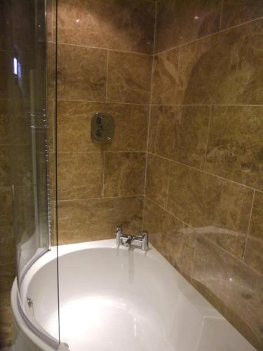a bathroom with a bath tub with a shower at Deerdale Lodge in Bilsthorpe