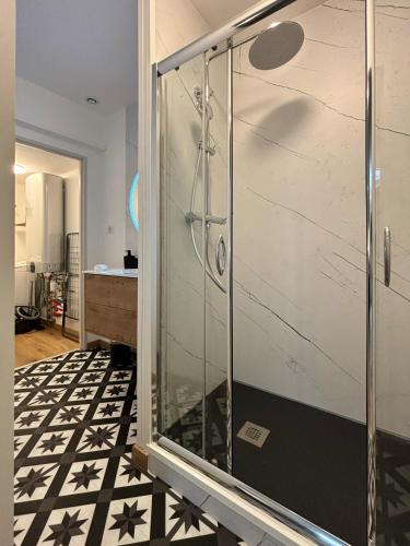 une douche avec une porte vitrée dans une salle de bain dans l'établissement Le Oliva chez les M by Primo Conciergerie, à Nevers