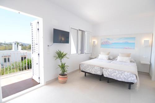 a white bedroom with a bed and a balcony at Apartamentos Casa Franziska in Talamanca