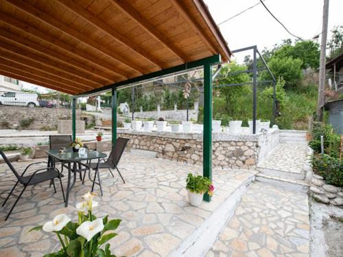 a patio with a table and chairs and a stone wall at Basil & Sunrise in Lazaráta