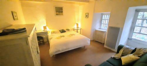a bedroom with a white bed and a couch at Authentique presbytére pour 6 personnes in Asperjoc