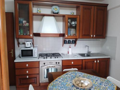 a kitchen with a stove and a sink and a table at MyrEma House - near Fontanarossa Airport Catania in Catania