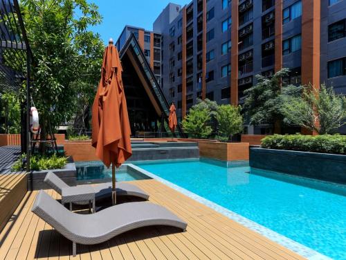 a pool with a chair and an umbrella next to a building at Central Festival Condo in Chiang Mai
