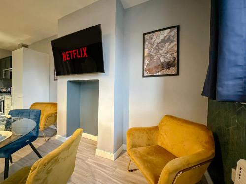 a living room with yellow chairs and a tv on the wall at Luxury Boutique Apartments Block Free Street Parking in Hounslow
