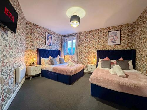 1 dormitorio con 2 camas y papel pintado con motivos florales en Luxury Boutique Apartments Block Free Street Parking en Hounslow