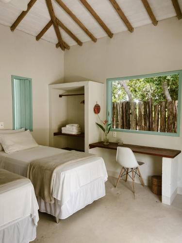 a bedroom with two beds and a chair and a window at Pousada Refazenda in Corumbau