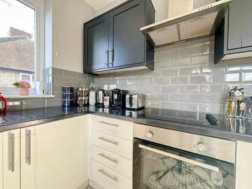 a kitchen with white cabinets and black appliances at Luxury Boutique Apartments Block Free Street Parking in Hounslow