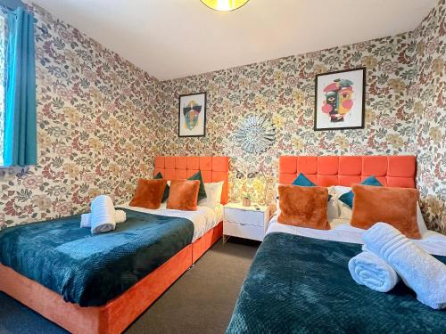 two beds in a bedroom with floral wallpaper at Luxury Boutique Apartments Block Free Street Parking in Hounslow