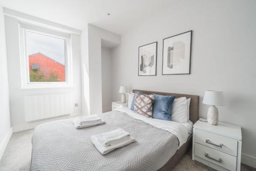 Lovely 1 Bedroom Apartment in Eastleigh Town Centre في إيستلي: غرفة نوم بيضاء مع سرير عليه منشفتين