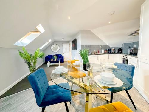 a kitchen and dining room with a glass table and blue chairs at Luxury Boutique Apartments Block Free Street Parking in Hounslow