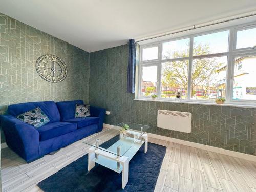 a living room with a blue couch and a clock on the wall at Luxury Boutique Apartments Block Free Street Parking in Hounslow
