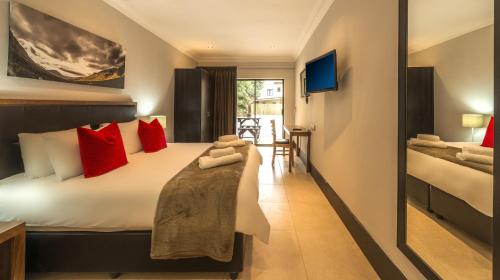 a bedroom with a large bed with red pillows at Clanwilliam Hotel in Clanwilliam