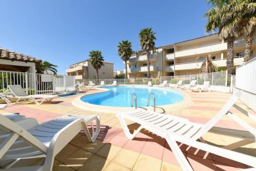 une piscine avec des chaises longues et un complexe hôtelier dans l'établissement Appartement 2CH, clim, piscine, garage, mer, au Grau-du-Roi