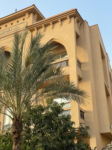 a building with a palm tree in front of it at Livingville The Two-Fifty in Cairo