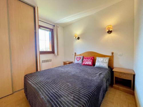 a bedroom with a bed with red pillows on it at Appartement Flumet, 2 pièces, 4 personnes - FR-1-505-206 in Flumet