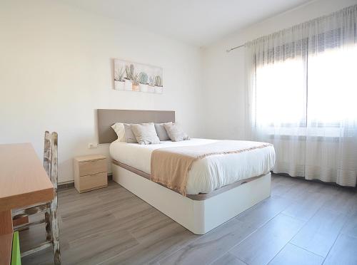 a white bedroom with a bed and a window at Casa de playa en un pequeño paraíso in Isla de Arosa