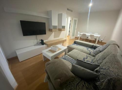 uma sala de estar com um sofá e uma televisão de ecrã plano em Balcón del atardecer em Barbate
