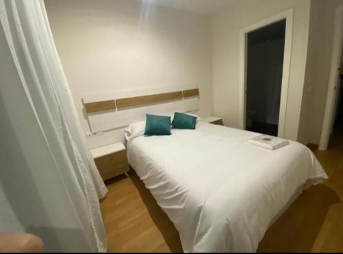 a bedroom with a white bed with two blue pillows at Balcón del atardecer in Barbate
