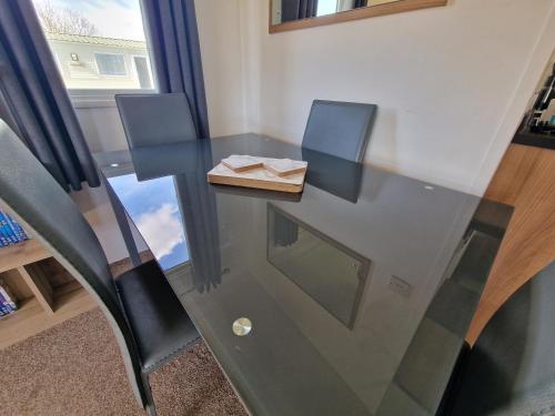 una mesa de cristal con 2 sillas y una caja de madera en B17 Sunnymede Caravan Park, Fantasy Island, Ingoldmells, en Ingoldmells