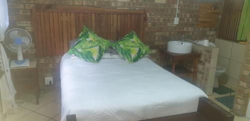 - une chambre avec un lit blanc et un lavabo dans l'établissement Silvex, à Piet Retief