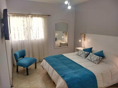 una camera da letto con un letto grande e una sedia blu di Alto Ramon a Neuquén