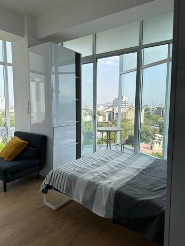 Schlafzimmer mit einem Bett, einem Stuhl und Fenstern in der Unterkunft Icon Cibeles in Mexiko-Stadt