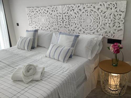 - un lit blanc avec un tas d'oreillers et une serviette dans l'établissement WHITE HOUSE IBIZA, à Nuestra Señora de Jesus