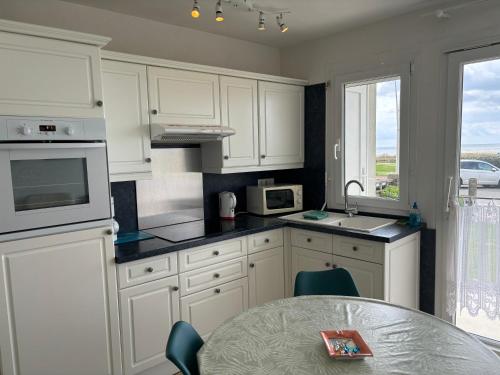 une cuisine avec des armoires blanches et une table dans l'établissement Studio en résidence face mer avec parking, à Le Touquet-Paris-Plage