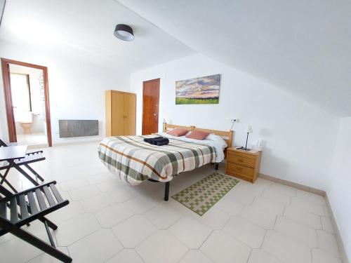 a white bedroom with a bed and a wooden dresser at Pensión El Pozo in Cudillero