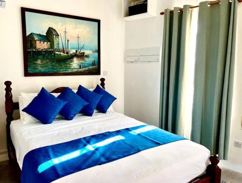 sypialnia z łóżkiem z niebieskimi poduszkami i obrazem w obiekcie Modern apt with view and easy beach access w mieście Port Elizabeth