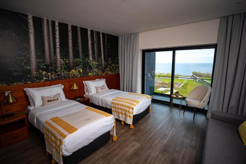 two beds in a hotel room with a view of the ocean at Xhale Azores in Angra do Heroísmo